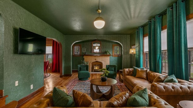 Una sala de estar acogedora con chimenea, sofás de cuero y un televisor montado en la pared.