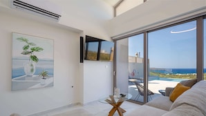 Un salon moderne avec une table en verre, un canapé et une grande fenêtre donnant sur la mer.