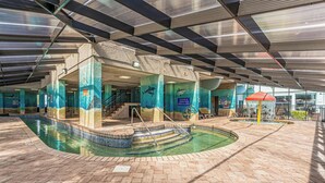 An indoor swimming pool with a tiled floor, a diving area, and a lifeguard station.
