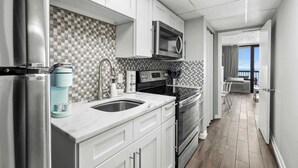 A modern kitchen with white cabinets, a microwave, a stove, and a sink.