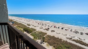 A beach with a wooden railing, sandy beach, and the ocean.