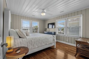 A bedroom with a bed, bedside table, lamp, and a television.