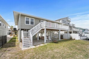 A two-story house with a covered porch, a staircase, and outdoor seating.