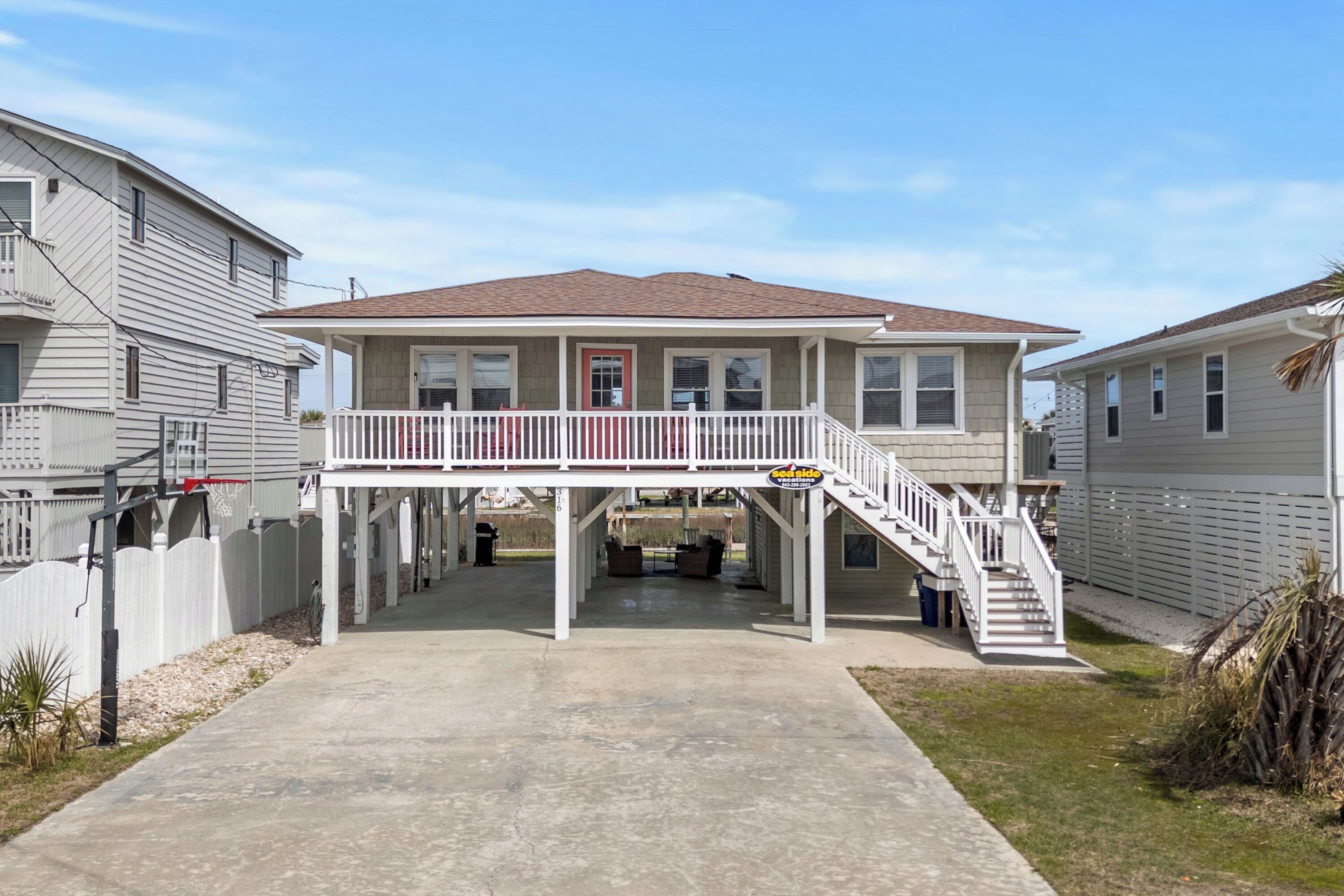 A two-story house with a covered patio, a staircase, and a fenced yard.