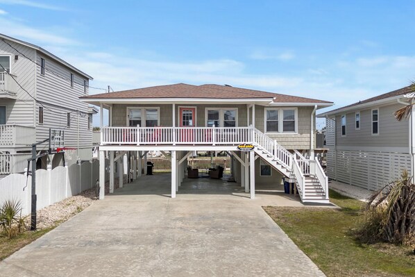 A two-story house with a covered patio, a staircase, and a fenced yard.