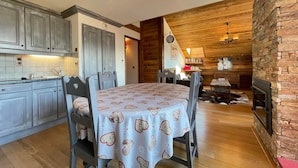 Una cocina acogedora con armarios de madera, una mesa de comedor con mantel estampado y una chimenea de piedra.