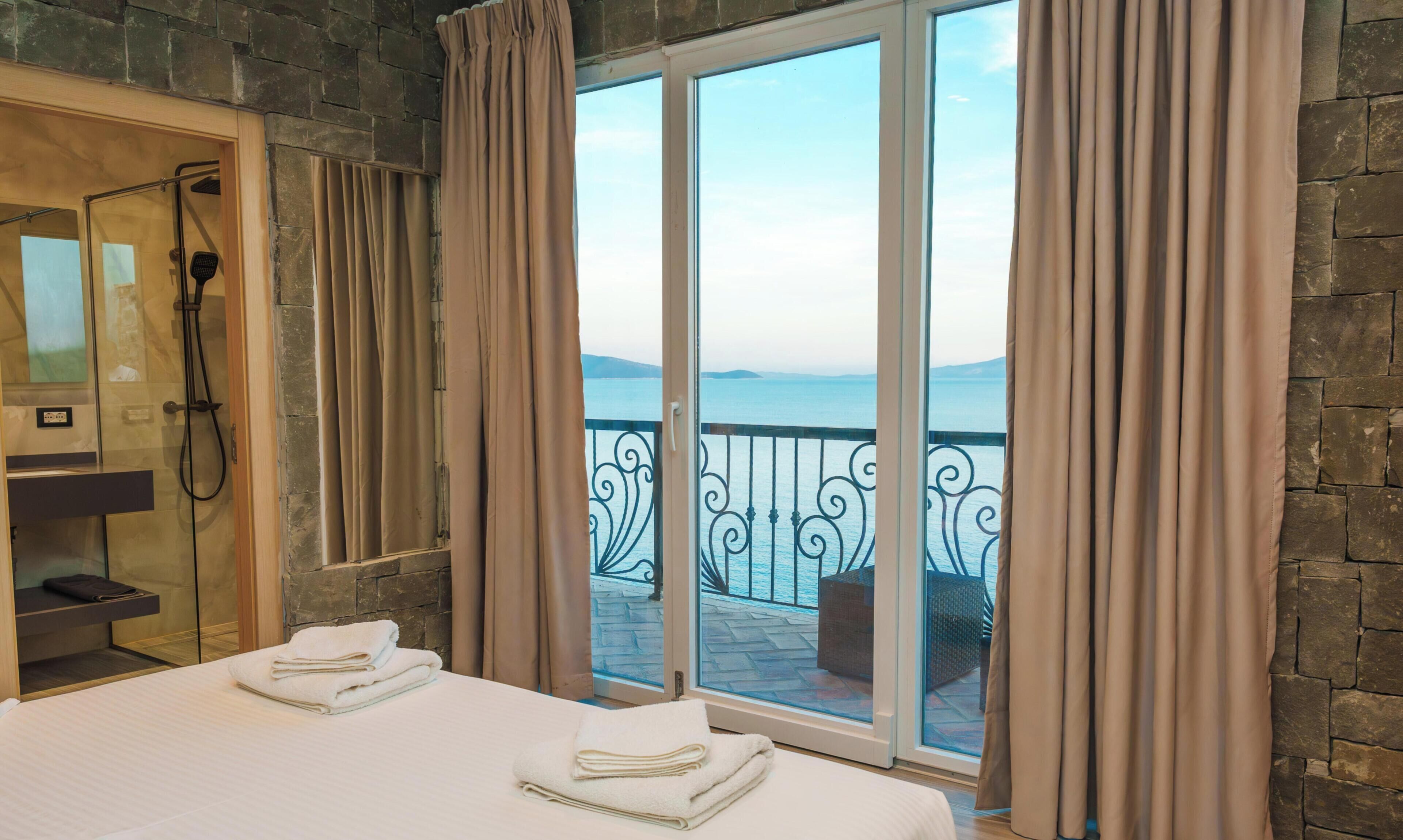 Une chambre d’hôtel avec un lit, une douche et un balcon donnant sur la mer.