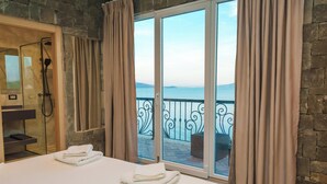 A hotel room with a bed, a shower, and a balcony with a view of the sea. - Kshira Oasis Qeparo - Boutique Beachfront Suites & Restaurant (Himare)