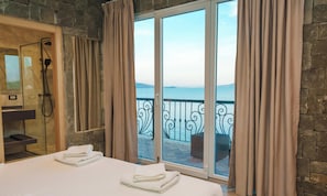 Une chambre d’hôtel avec un lit, une douche et un balcon donnant sur la mer.