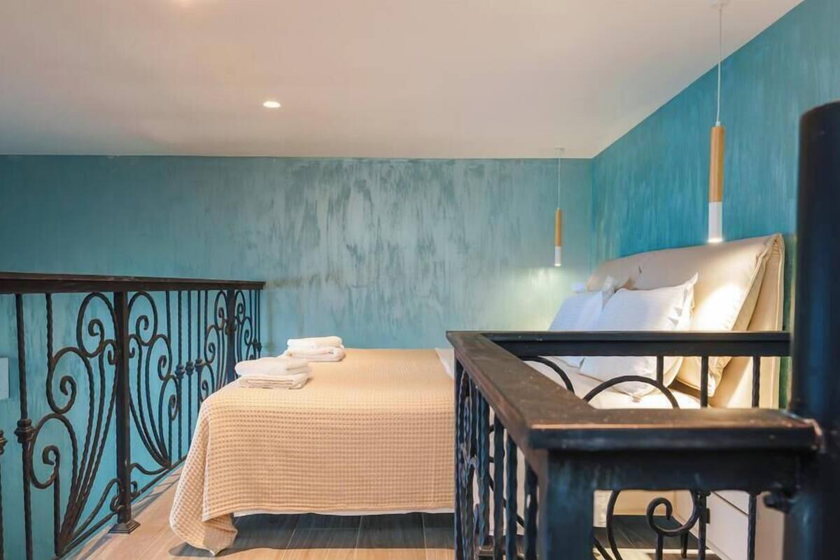 Un dormitorio con cama, mesita de noche, ventana y barandilla de balcón.