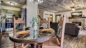 A rustic dining area with a glass table, wooden chairs, and a chandelier. - Arcadian Pass, “Cozy Cabin Retreat in the Smokies – Comfort & Fun for All” (Sevierville)