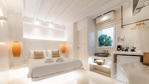 Ein modernes Schlafzimmer mit einem großen Bett, Nachttischlampen, einem kleinen Tisch und Blick ins Freie.
