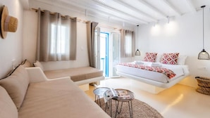 Ein modernes Schlafzimmer mit einem Bett, einem Sofa, einem kleinen Tisch und einem Fenster mit Vorhängen.