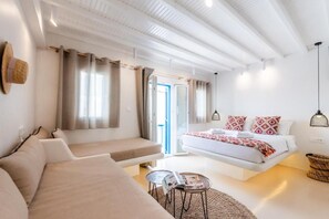 Een moderne slaapkamer met een bed, een bank, een kleine tafel en een raam met gordijnen.