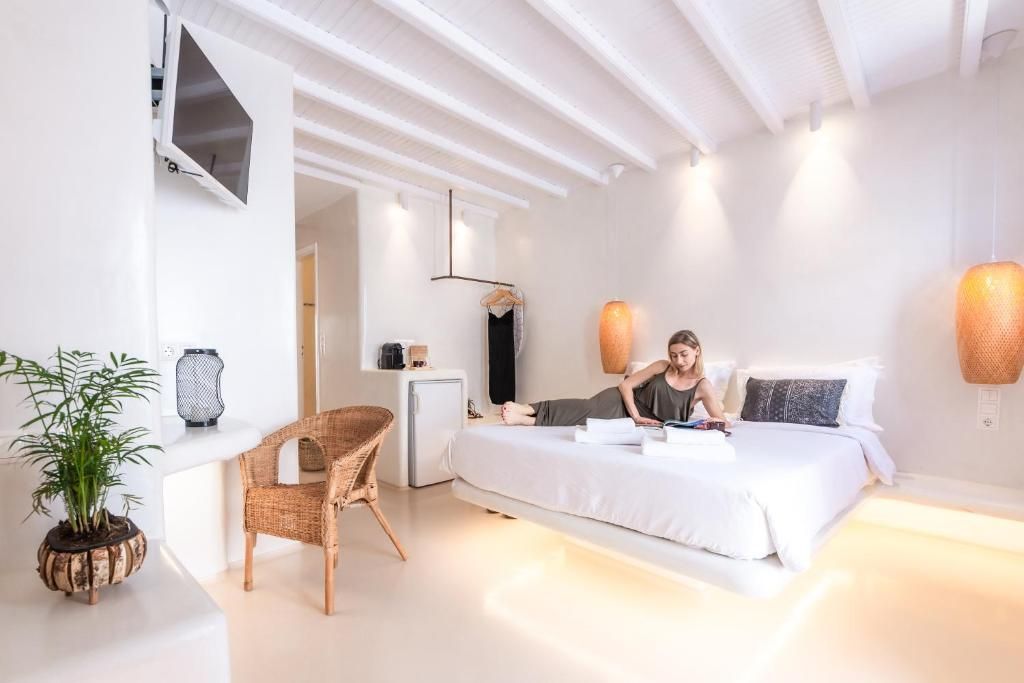 Una habitación de hotel moderna con cama, escritorio, silla y una planta en maceta.