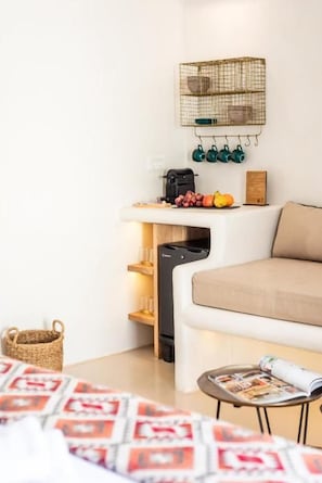 A compact room with a white sofa, a small table with a magazine, a coffee machine, and a basket. - Anastasia's Visage Mykonos (Mykonos Town, Mykonos, Greece)