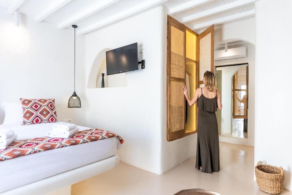 A hotel room with a bed, a television, a large window, and a wardrobe.