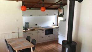 A cozy kitchen with wooden cabinets, a dining table, and a black stove.