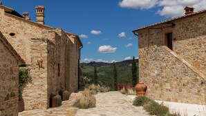 Un estrecho sendero de piedra entre edificios, con una vista despejada del campo.