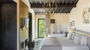 Un dormitorio moderno con una cama grande, una araña y vistas a zonas verdes.