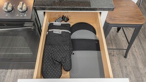 A kitchen drawer with black oven mitts, a black pot holder, and a black spatula. - Secluded ½-acre retreat surrounded by trees for ultimate privacy and quiet. Remodeled and beautifully furnished with modern finishes. Enjoy a peaceful setting just 8 minutes from Belton/Raymore—perfect for relaxing stays or extended work trips. (Grandview)