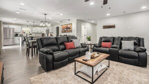 A spacious living area with two black leather sofas, a wooden coffee table, and a ceiling fan. - Secluded ½-acre retreat surrounded by trees for ultimate privacy and quiet. Remodeled and beautifully furnished with modern finishes. Enjoy a peaceful setting just 8 minutes from Belton/Raymore—perfect for relaxing stays or extended work trips. (Grandview)