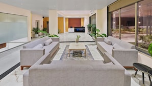 Een moderne lobby met een receptiebalie, banken en potplanten.