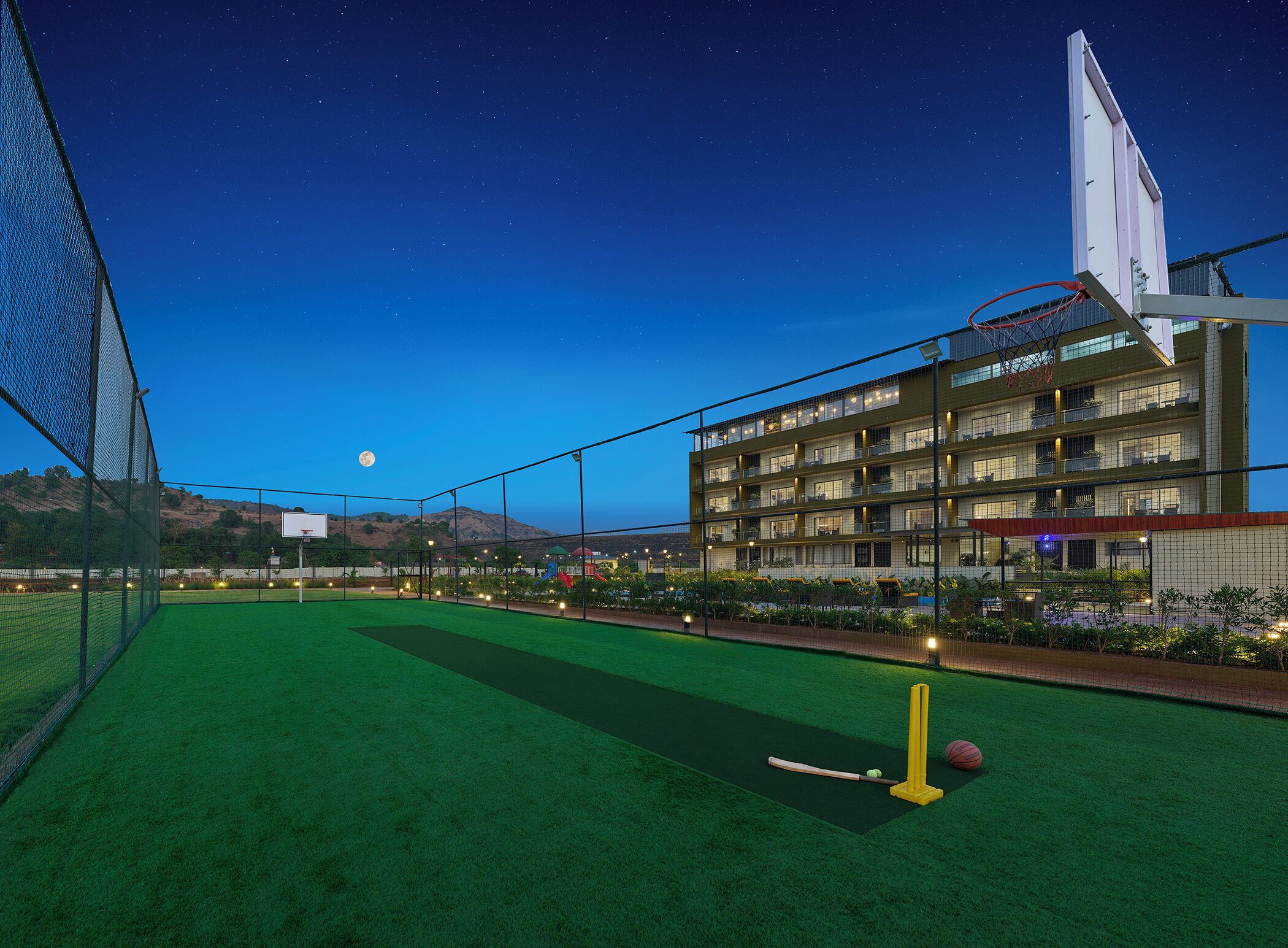 Una cancha deportiva con una red, un campo de cricket y un aro de baloncesto.