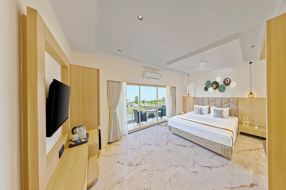 Una habitación de hotel moderna con una cama grande, televisión de pantalla plana, espacio para café y un balcón con vistas.