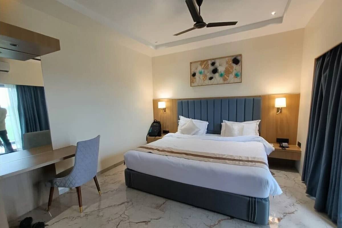Una habitación de hotel con cama, escritorio, silla y dos lámparas de noche.