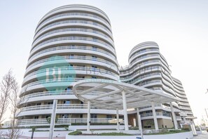 A modern multi-story hotel with a distinctive curved facade and a covered outdoor area.