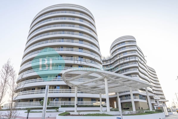 A modern multi-story hotel with a distinctive curved facade and a covered outdoor area.