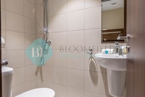 A bathroom with a toilet, a shower, and a sink.