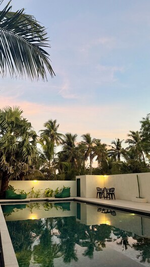 A swimming pool with a view of palm trees and a sunset. - Nilaveli Boutique Hotel  (Nilaveli)