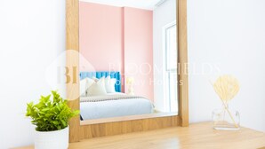 Une chambre à coucher comprenant un lit, une table de chevet, un miroir, une plante en pot et un objet décoratif.