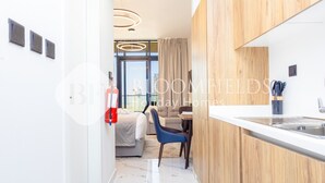 A modern kitchen with a white countertop, wooden cabinets, and a built-in sink. - Bloomfields STU In Al Maryah Island Escape (Abu Dabi)
