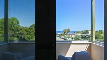 Un balcon avec vue sur la mer et la verdure.