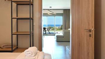 Une chambre d’hôtel avec un lit, une étagère en bois et une vue sur l’océan par de grandes fenêtres.