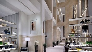 A modern hotel lobby with a central seating area, a reception desk, and a large display of decorative items.