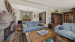 A living room with two blue sofas, a wooden coffee table, a fireplace, and a dining area with a table and chairs. - House for 10 with large garden, 250m from the sea (Louannec)