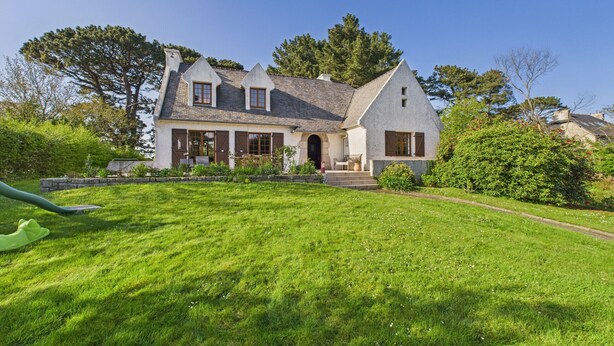 A large, two-story house with a steeply pitched roof, a prominent chimney, and a well-maintained lawn. - House for 10 with large garden, 250m from the sea (Louannec)