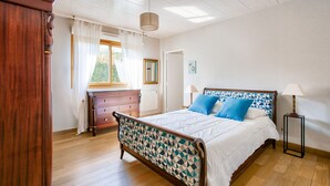 A bedroom with a wooden bed, a dresser, a nightstand, and a window with curtains. - 600m from the beach, garden, house for 10 (Saint-Briac-sur-Mer)
