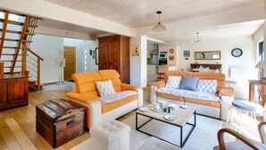 A spacious living room with two sofas, a coffee table, and a wooden chest. A staircase leads to another room. - 600m from the beach, garden, house for 10 (Saint-Briac-sur-Mer)