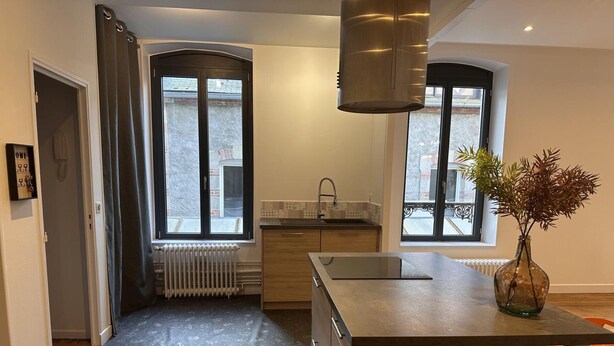 A modern kitchen with a central island, a built-in oven, and a window with a view of the street. - Modern city-center gîte in Moulins for 4 with Wifi (Moulins)