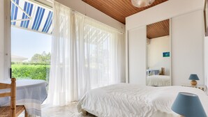 Une chambre avec un lit, une chaise, une table et une vue sur la verdure.