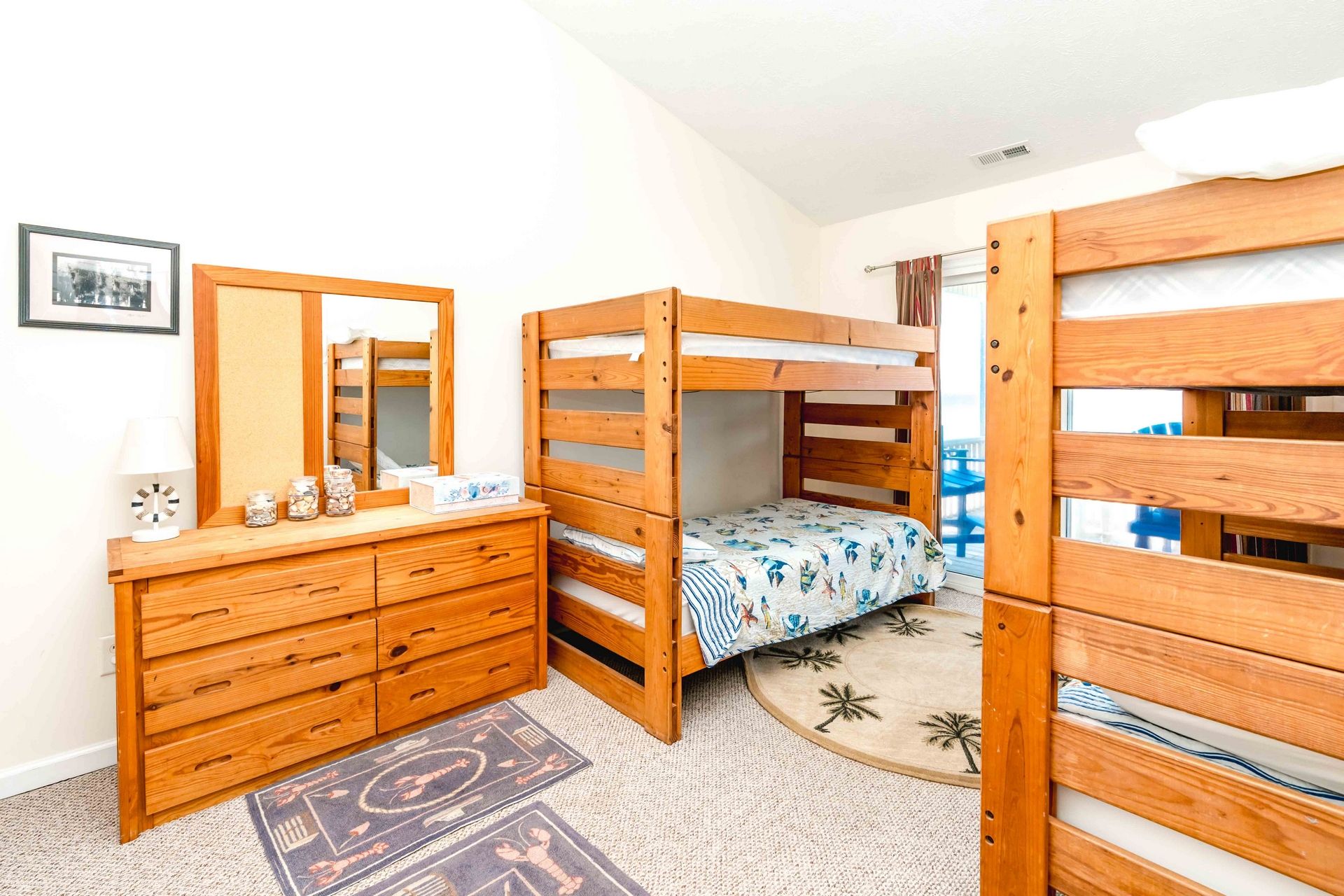 A bedroom with bunk beds, a wooden dresser, a mirror, and a small rug.