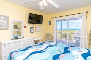 A bedroom with a bed, a television, a chair, and a balcony with a view of the ocean. - The Sugar Shak - 4 BR Oceanfront Home with Covered Porch (Surf City)