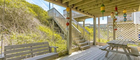 A wooden deck with a picnic table and benches, a staircase, and a wooden fence.