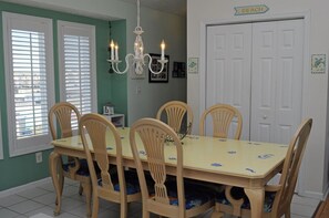 A dining room with a table and chairs, a chandelier, and a door labeled 'BEACH'. - The Sugar Shak - 4 BR Oceanfront Home with Covered Porch (Surf City)