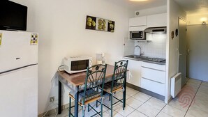 A compact kitchen with a microwave, sink, and a dining area with chairs.